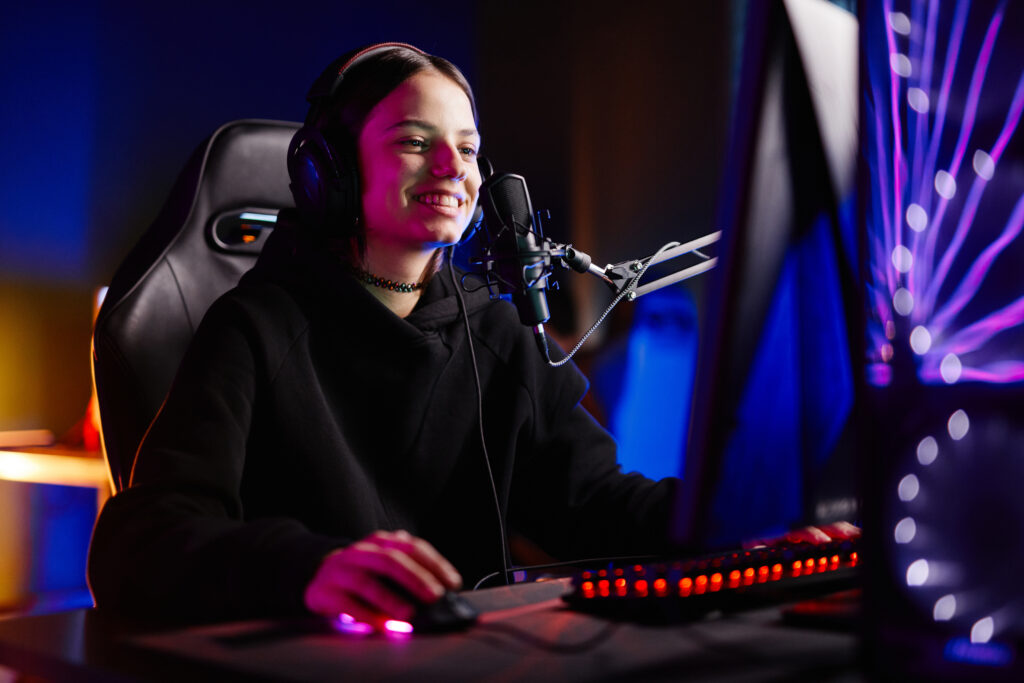 Portrait of female streamer playing video games in dark studio with neon accents