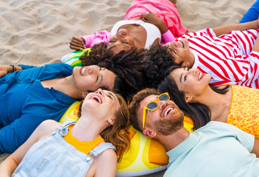 Multiethnic group of young happy friends bonding outside, having fun on summertime vacation.