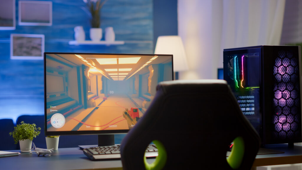 RGB powerful personal computer gamer rig with first-person shooter game on screen. 