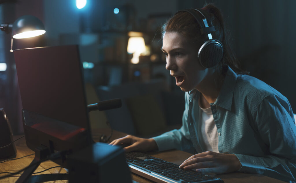 Cheerful girl playing online video games at home